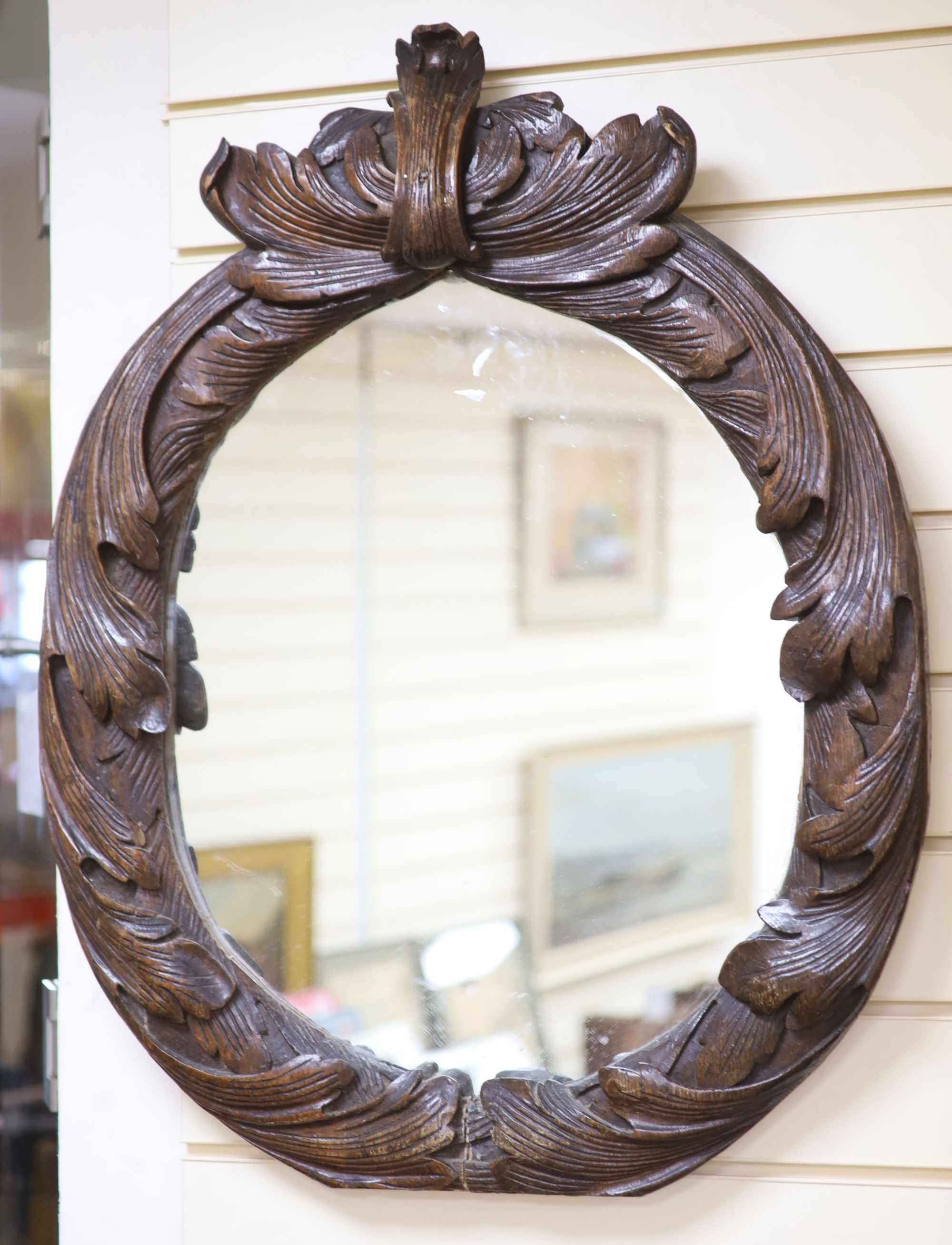 An early 19th century oval carved wall mirror